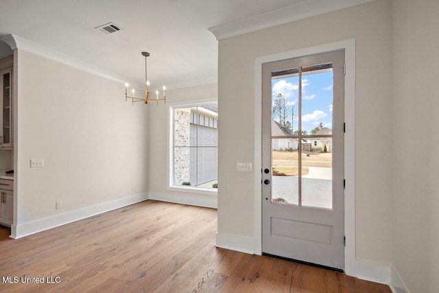 entryway featuring light wood finished floors, visible vents, a wealth of natural light, and ornamental molding