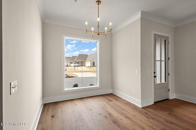 unfurnished dining area featuring ornamental molding, a notable chandelier, and wood finished floors