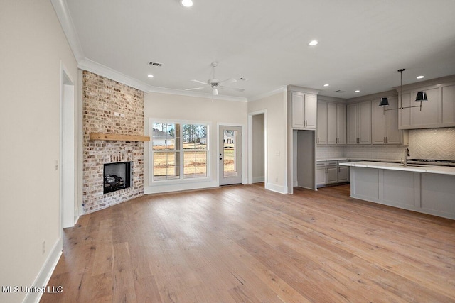 kitchen featuring open floor plan, light countertops, a brick fireplace, gray cabinets, and decorative light fixtures