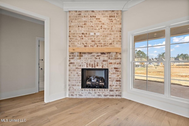 unfurnished living room featuring a brick fireplace, light wood-style flooring, and baseboards