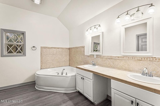 bathroom featuring a bath, vaulted ceiling, decorative backsplash, vanity, and hardwood / wood-style flooring