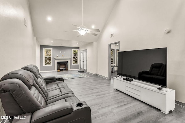 living room with light hardwood / wood-style floors, high vaulted ceiling, and ceiling fan