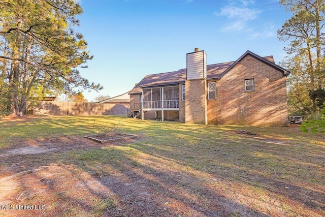 rear view of property featuring a sunroom and a yard