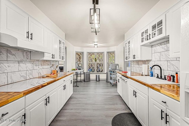 kitchen with pendant lighting, wood counters, white cabinets, and sink