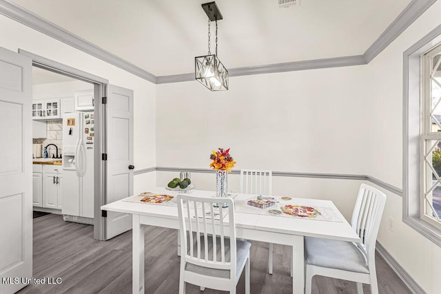 dining room with wood-type flooring, a wealth of natural light, and crown molding