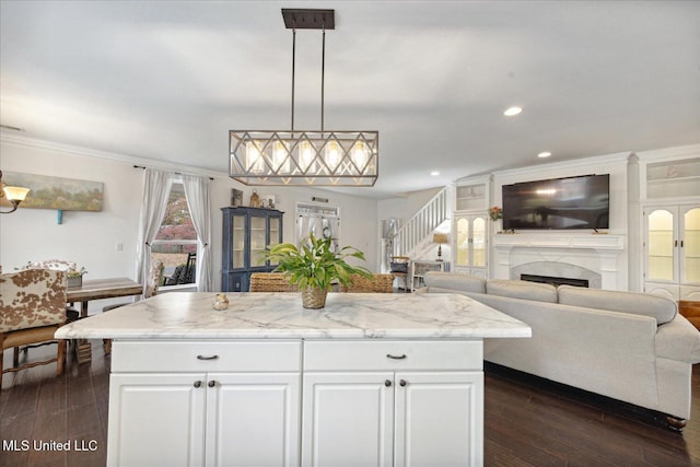 kitchen featuring white cabinets, decorative light fixtures, a kitchen island, and dark wood-type flooring