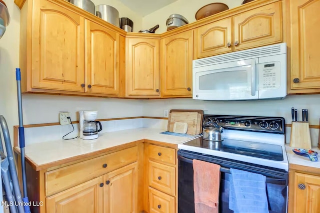 kitchen with light countertops, white microwave, light brown cabinetry, and electric range oven