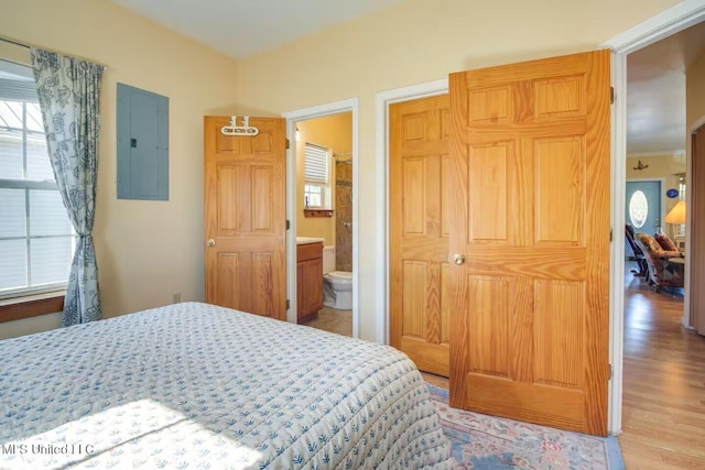 bedroom featuring ensuite bath, electric panel, and wood finished floors