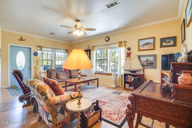 living area with crown molding, wood finished floors, a healthy amount of sunlight, and visible vents