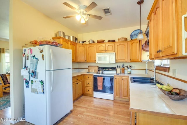 kitchen featuring white appliances, visible vents, light wood-style flooring, a sink, and decorative light fixtures