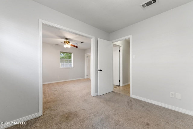 empty room featuring visible vents, a ceiling fan, baseboards, and light carpet