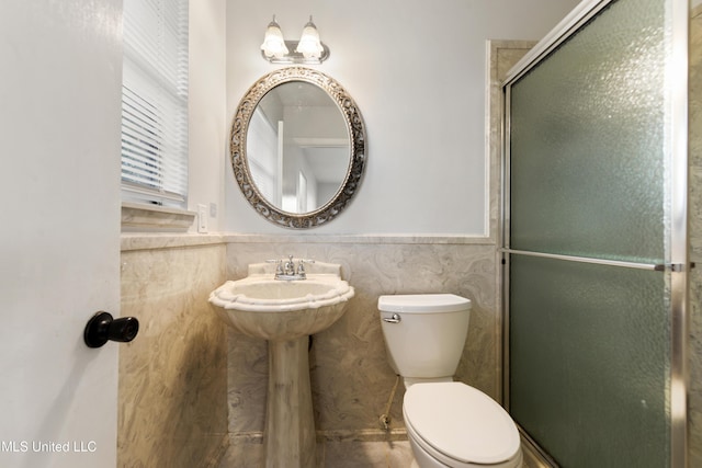 full bath featuring an enclosed shower, a wainscoted wall, toilet, and tile walls