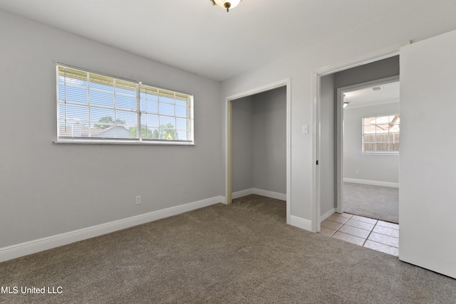 unfurnished bedroom with carpet floors, baseboards, tile patterned flooring, and a closet