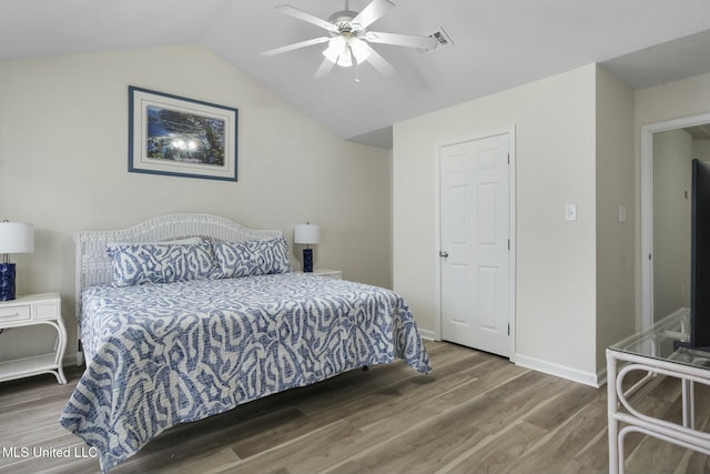 bedroom with visible vents, baseboards, wood finished floors, and vaulted ceiling