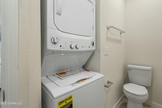 washroom with stacked washer / drying machine, baseboards, and laundry area