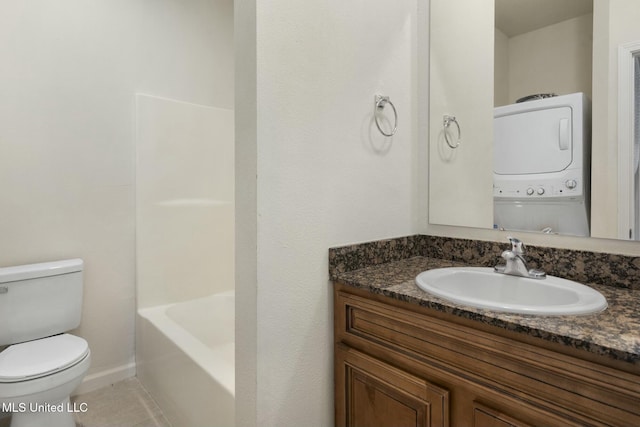 bathroom featuring tile patterned floors, toilet, stacked washer / drying machine, baseboards, and vanity