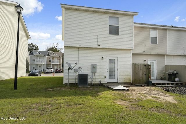 rear view of property with cooling unit, a lawn, and fence