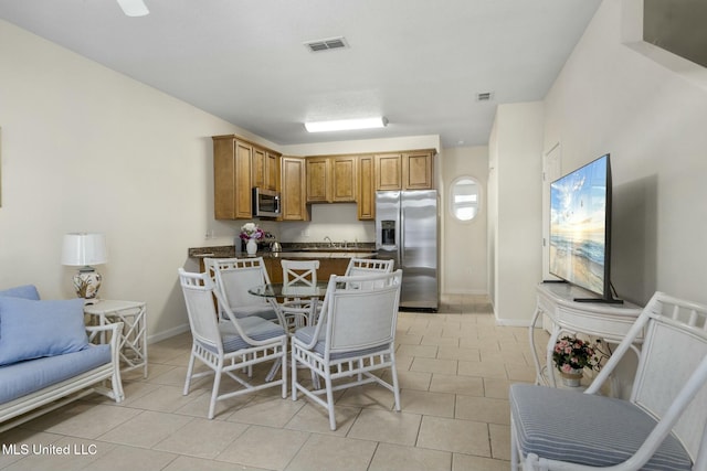 kitchen with light tile patterned floors, brown cabinetry, visible vents, appliances with stainless steel finishes, and dark countertops