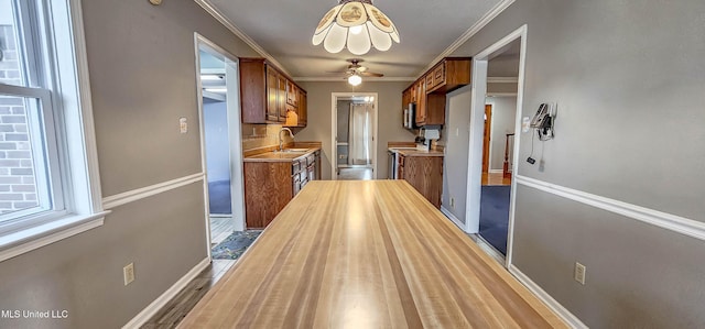 kitchen featuring ceiling fan, sink, stainless steel appliances, crown molding, and wood-type flooring