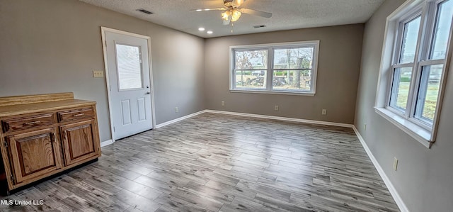 interior space featuring ceiling fan, a textured ceiling, and light hardwood / wood-style flooring