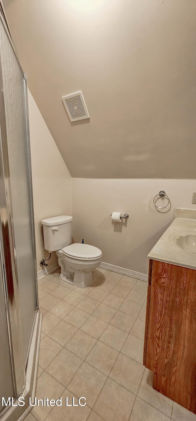 bathroom featuring tile patterned floors, vanity, vaulted ceiling, a shower with door, and toilet