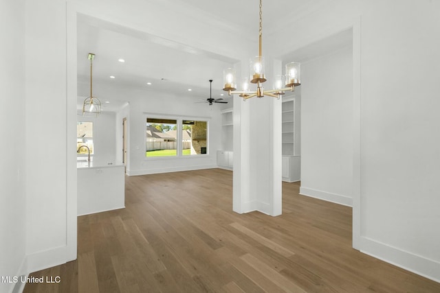 unfurnished dining area with hardwood / wood-style floors and ceiling fan with notable chandelier