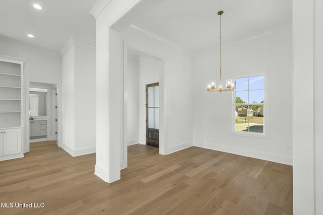 unfurnished dining area with a chandelier, light hardwood / wood-style floors, and ornamental molding