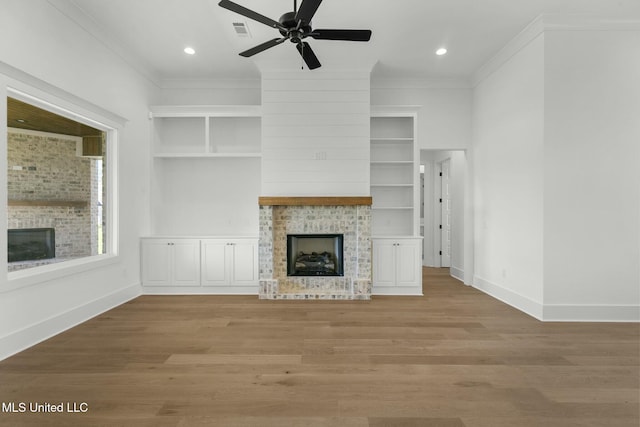 unfurnished living room with a large fireplace, ornamental molding, and light hardwood / wood-style flooring