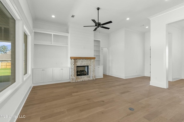 unfurnished living room featuring a fireplace, light hardwood / wood-style flooring, ceiling fan, and crown molding