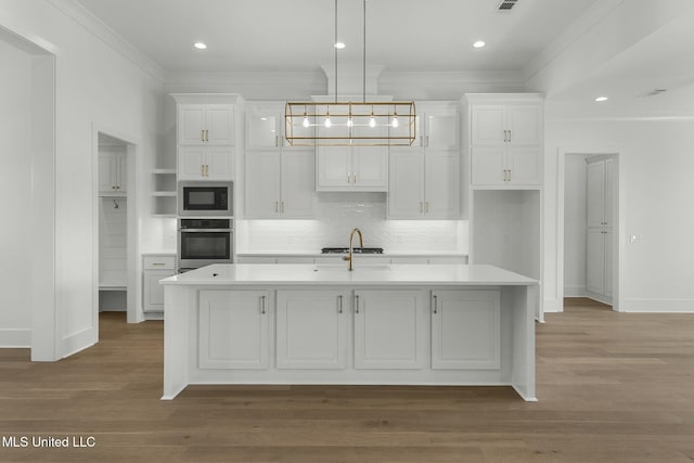 kitchen with appliances with stainless steel finishes, hardwood / wood-style flooring, and a kitchen island with sink