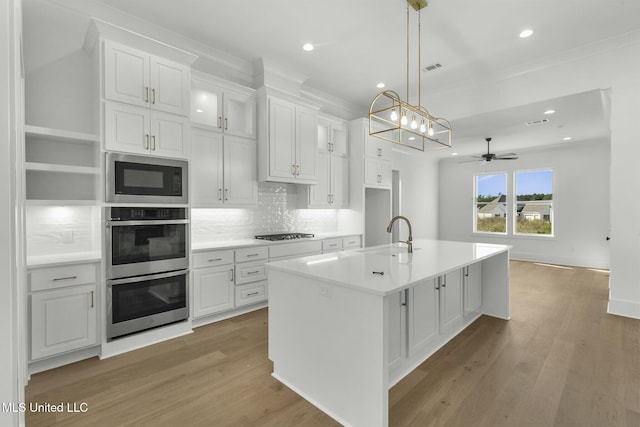 kitchen with a center island with sink, white cabinets, black appliances, ceiling fan, and light wood-type flooring