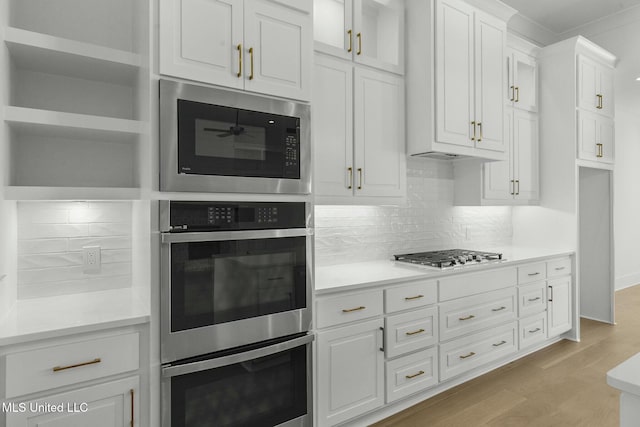 kitchen with tasteful backsplash, white cabinets, stainless steel appliances, and light hardwood / wood-style floors