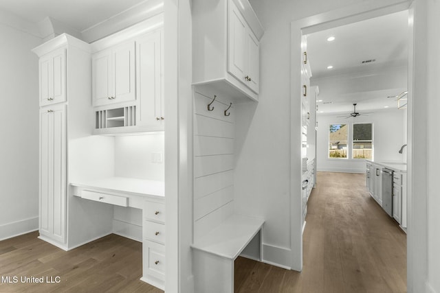 mudroom with ceiling fan, dark hardwood / wood-style flooring, built in desk, and ornamental molding