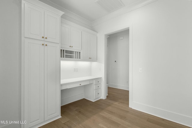 interior space featuring light wood-type flooring, built in desk, and crown molding