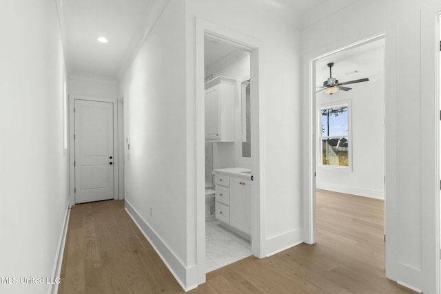 corridor featuring light wood-type flooring and ornamental molding