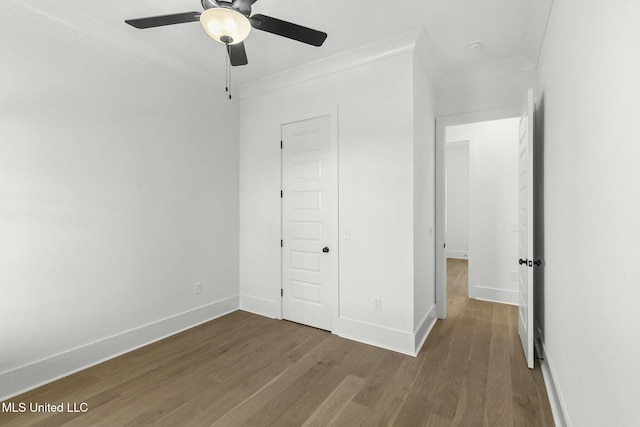 unfurnished bedroom with wood-type flooring, a closet, ceiling fan, and crown molding