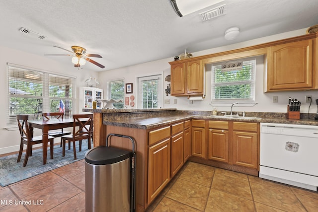11334 Texas St, Bay Saint Louis, MS 39520 - kitchen featuring white dishwasher, a peninsula, dark countertops, a ceiling fan, and plenty of natural light