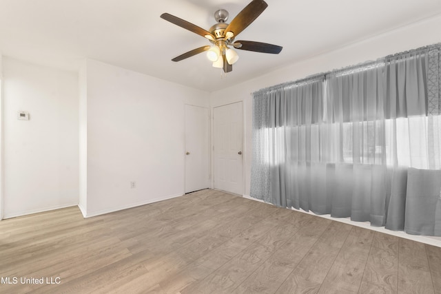 unfurnished room with a ceiling fan, wood finished floors, and baseboards