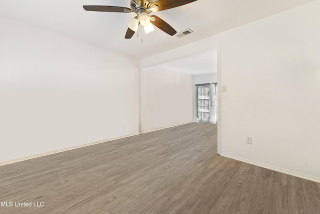 spare room featuring ceiling fan, wood finished floors, visible vents, and baseboards