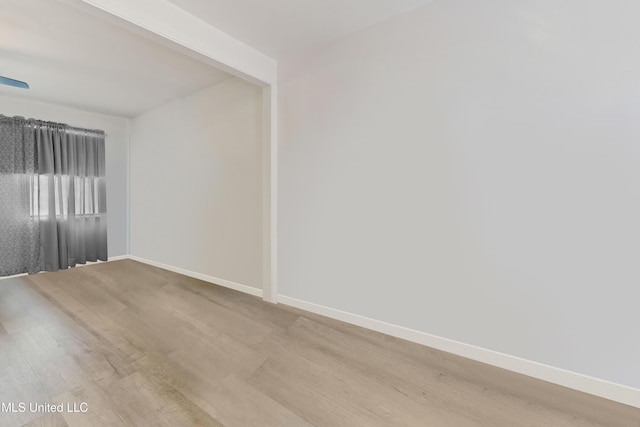 empty room with beamed ceiling, baseboards, and wood finished floors