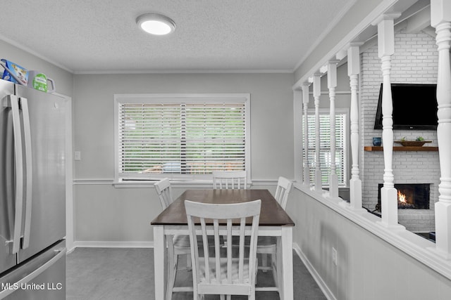 dining area with a textured ceiling, a fireplace, a wainscoted wall, and ornamental molding