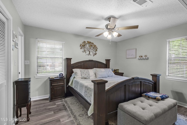bedroom featuring wood finished floors, a textured ceiling, a ceiling fan, and baseboards