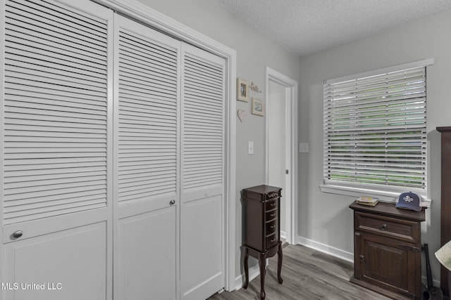 interior space featuring wood finished floors, a textured ceiling, and baseboards