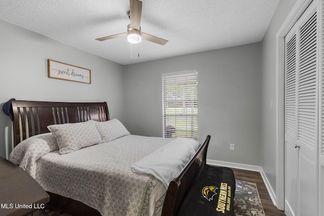 bedroom featuring a closet, dark wood-type flooring, a textured ceiling, baseboards, and ceiling fan