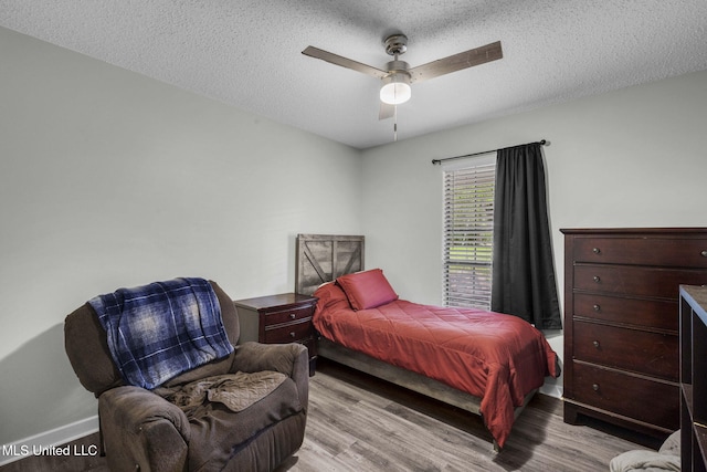 bedroom with wood finished floors, baseboards, a textured ceiling, and a ceiling fan