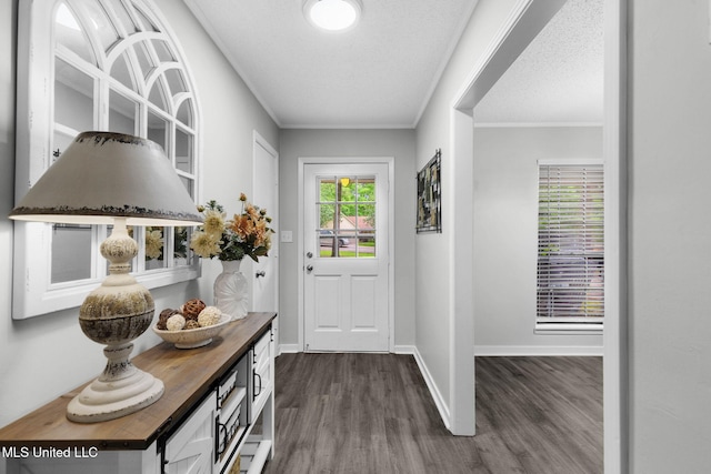 doorway with dark wood-type flooring, crown molding, and baseboards