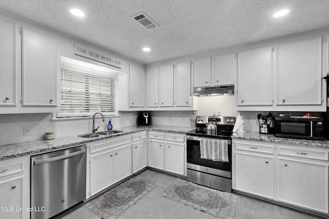kitchen featuring stainless steel appliances, under cabinet range hood, a sink, white cabinetry, and recessed lighting