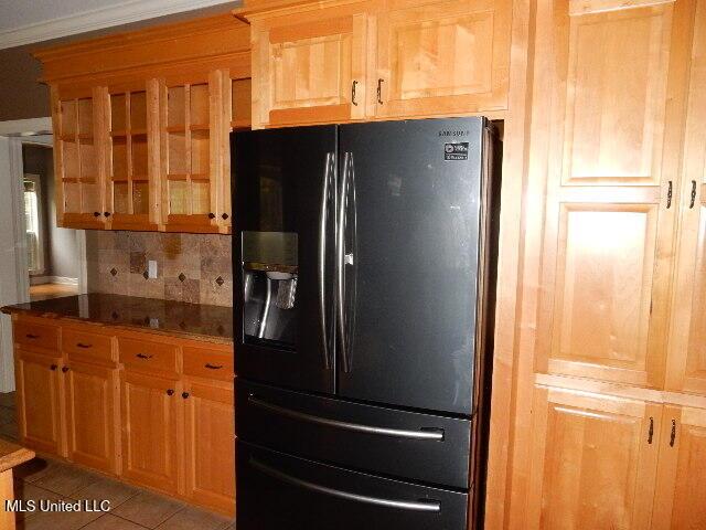 8 Auburn Ln, Hattiesburg, MS 39401 - kitchen with black fridge, tasteful backsplash, glass insert cabinets, light tile patterned floors, and dark stone counters