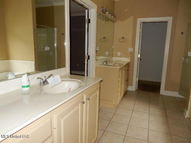 8 Auburn Ln, Hattiesburg, MS 39401 - bathroom with a shower stall, tile patterned floors, two vanities, and ornamental molding