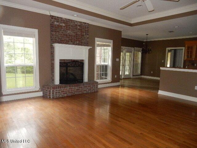 8 Auburn Ln, Hattiesburg, MS 39401 - unfurnished living room featuring wood finished floors, a ceiling fan, a chandelier, crown molding, and baseboards